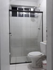 a bathroom with a toilet and a glass shower at Kit Ocian in Praia Grande
