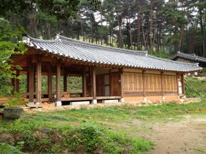 un pequeño edificio de madera con techo en un bosque en Korean Traditional House - Chungnokdang, en Boseong