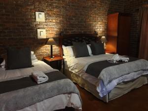 a bedroom with two beds and a brick wall at Sundowners Game Lodge in Marble Hall +28 photos