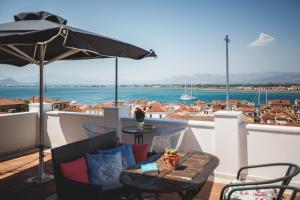 a balcony with an umbrella and a table and chairs at Porto Bello Nafplio in Nafplio