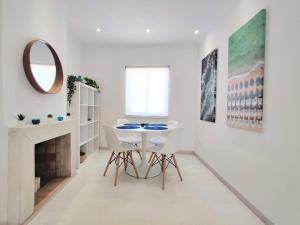 a white dining room with a table and a mirror at Casa Sequeira in Albufeira