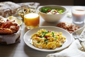 a table topped with a plate of scrambled eggs and bread at Liebeskind Boutique Hotel Old Town in Krakow