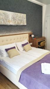 a bedroom with a large bed with white sheets and pillows at DeMar Apart Violet in Lviv