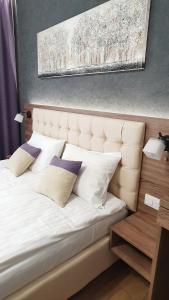 um quarto com uma cama branca com almofadas em DeMar Apart Violet em Lviv