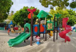 a playground with colorful playground equipment in a park at La Isla Tropica in Guraidhoo