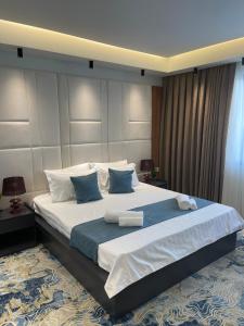 a bedroom with a large bed with blue and white pillows at Apartments Jordan Luxury in Gevgelija