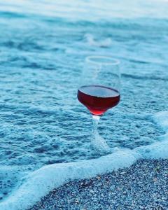 Black Sea View Costinesti في كوستينيشت: كأس من النبيذ تجلس على الرمال بالقرب من الماء