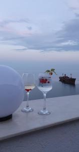 Black Sea View Costinesti في كوستينيشت: كأسين من النبيذ يجلسون على طاولة بالقرب من الماء