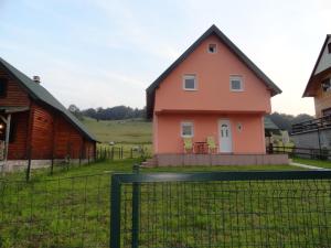a pink house with a fence in front of it at Guest House Happy in Žabljak