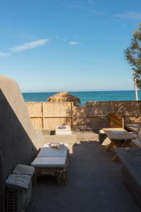 a patio with a couch and tables and the ocean at Demilmar Luxury Suites in Perissa