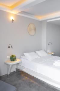 a white bedroom with a bed and a table at Demilmar Luxury Suites in Perissa