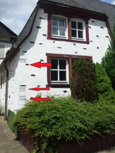 a white house with two red arrows on the side of it at Altes Fährhaus an der Mosel anno1633 in Traben-Trarbach