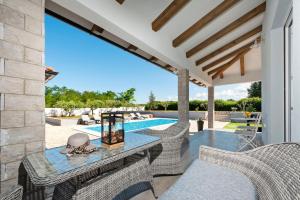 een terras met een tafel en stoelen en een zwembad bij Villa Miracolo in Rovinj