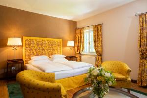 Un dormitorio con una cama y una mesa con un jarrón de flores en Der Knappenhof - Hotel & Restaurant, en Reichenau