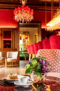 a table with a vase of flowers and cups of coffee at Der Knappenhof - Hotel & Restaurant in Reichenau