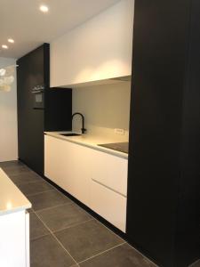 une cuisine avec des placards blancs et un mur noir dans l'établissement bloc 79/one, à Knokke-Heist