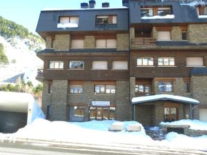 a large building with snow in front of it at Principat-Vacances Pirinenca in Incles