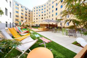 a patio with lawn chairs and tables and buildings at Hotel Zeitgeist Vienna Hauptbahnhof in Vienna