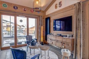 een woonkamer met een televisie en een tafel en stoelen bij La Petite Galerie - Magnifique Duplex avec balcon vue montagne - Flumet in Flumet