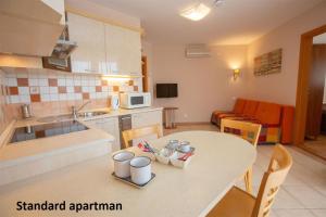 a kitchen with a table with chairs and a counter top at Liza Apartmanok in Hajdúszoboszló