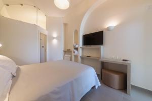 a bedroom with a white bed and a television at Insula Boutique Hotel in Procida