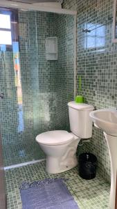 Baño de azulejos verdes con aseo y lavamanos en Suíte Ninho do Sabiá, en Ilhabela