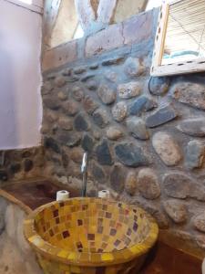 uma casa de banho com um lavatório amarelo numa parede de pedra em La Casa de Vero em Cachí