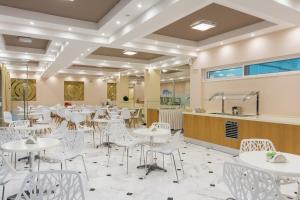 カラマキにあるRoseland Hotelの白いテーブルと白い椅子が備わるレストラン