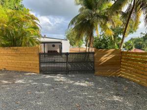 a fence in front of a house with palm trees at VILL'ARBOREE in Les Abymes