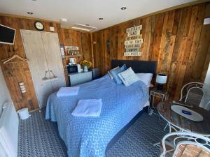 a bedroom with a blue bed and wooden walls at Pinecones Cosy B&B in Valley