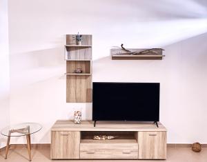 TV en un centro de entretenimiento de madera en una sala de estar en apus apartments, en Lefkada