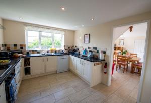 a large kitchen with white cabinets and a table at Avocet House in West Lulworth