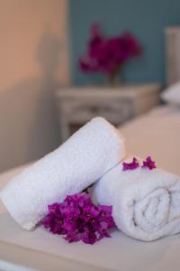 biały ręcznik i fioletowe kwiaty na łóżku w obiekcie Mema's Home -2 bedrooms- with stunning sea view w mieście Agia Efimia