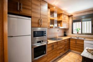 una cocina con armarios de madera y electrodomésticos de acero inoxidable en Apartamentos Maribel, en Calaceite