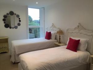 two beds with red pillows in a bedroom at Luxurious Cambridge City Centre 2 Bed Apartment with Balcony, Lift, Free Parking, Fast WIFI & Sleeps 6 in Cambridge