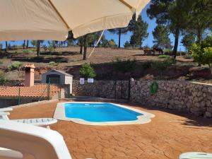 een zwembad in een tuin met een grote parasol bij Casa Rural Cortijo La Tapia in Riópar