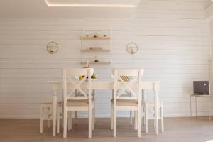 a white dining room table with two white chairs at Lake House Senec in Senec