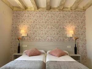 sypialnia z 2 łóżkami i ścianą z kwiatami w obiekcie Casa Rural Mugarri w mieście Poveña