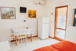 a kitchen with a table and a white refrigerator at Residence Villa la Palmas in Porto Azzurro