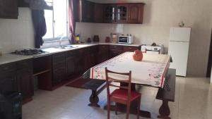 a kitchen with a table and a white refrigerator at Casa da Charneca da Caparica in Charneca