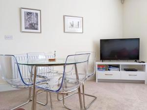 una mesa y sillas en una sala de estar con TV en The Coach House Flat, Chichester en Chichester