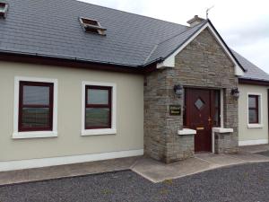 Cette maison individuelle présente une façade en briques et en pierre. dans l'établissement Killard House, à Caherlean