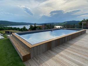 a swimming pool on a deck with a view of a lake at JBX Resort Apartments Lipno in Lipno nad Vltavou