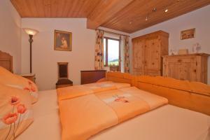 ein Schlafzimmer mit einem großen Bett mit orangefarbener Bettwäsche in der Unterkunft Ferienwohnungen Schneider in Kirchdorf in Tirol
