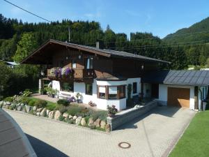 a house in the mountains with a driveway at Ferienwohnungen Schneider in Kirchdorf in Tirol