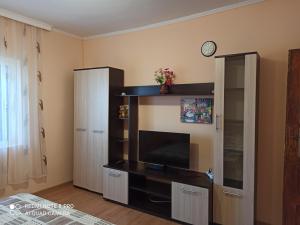 uma sala de estar com televisão de ecrã plano num centro de entretenimento em Къща за гости Феникс em Shabla