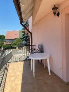 - Balcón con mesa blanca y sillas en Abigél Apartmanház, en Balatonfüred