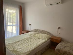 a small bedroom with a bed and a window at Abigél Apartmanház in Balatonfüred