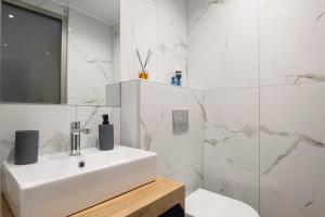 a white bathroom with a sink and a toilet at Epohikon Studios in Sarti
