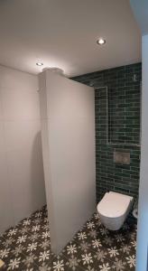 a bathroom with a toilet and a black tile wall at B&B 't Speulderbos in Ermelo